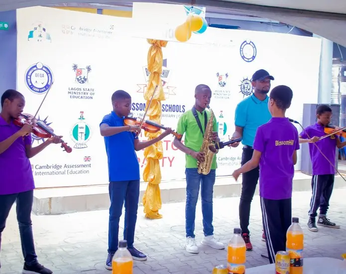Students playing violins and a saxophone together at a school performance